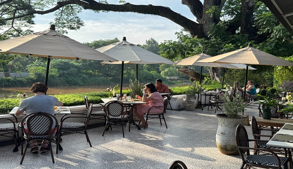 A massive rain tree stands adjacent to the resort’s riverside dining terrace