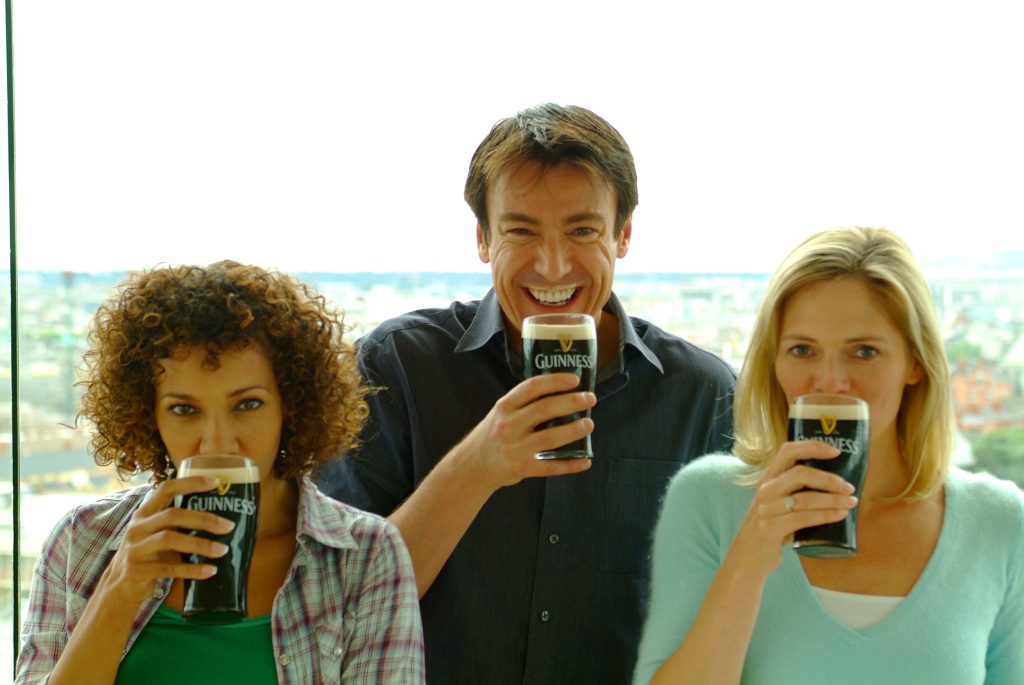 Friends sipping pints, man with pint moustache in the Gravity Bar, Guinness Storehouse, madly