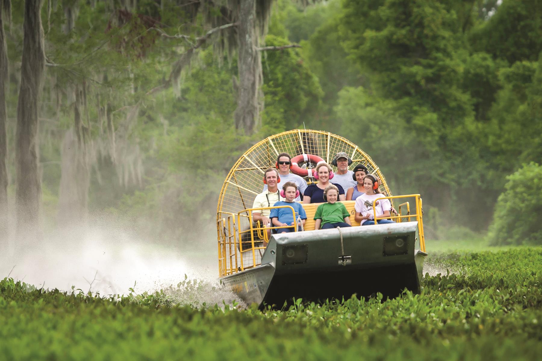 Tourists ride an airboat through the cypress forest of Henderson Swamp - outdoor adventure