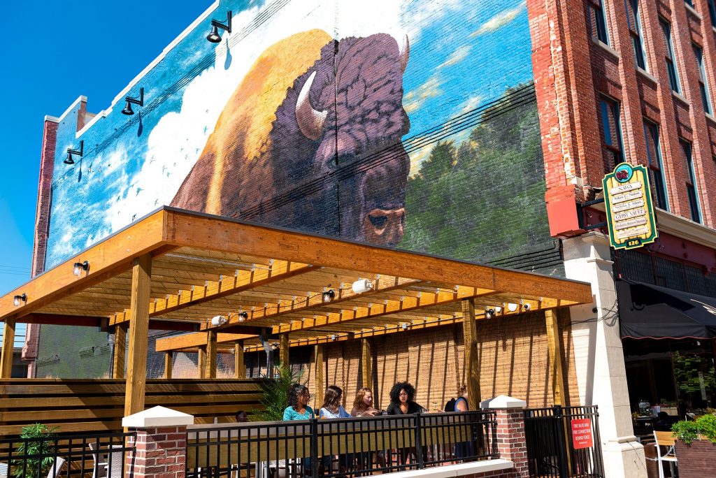 The Landing, a renovated warehouse district, has some of Fort Wayne’s most talked about restaurants. Show here below the buffalo mural is the patio at Nawa, which serves up the flavors of Asia. (Photo credit: Visit Fort Wayne)