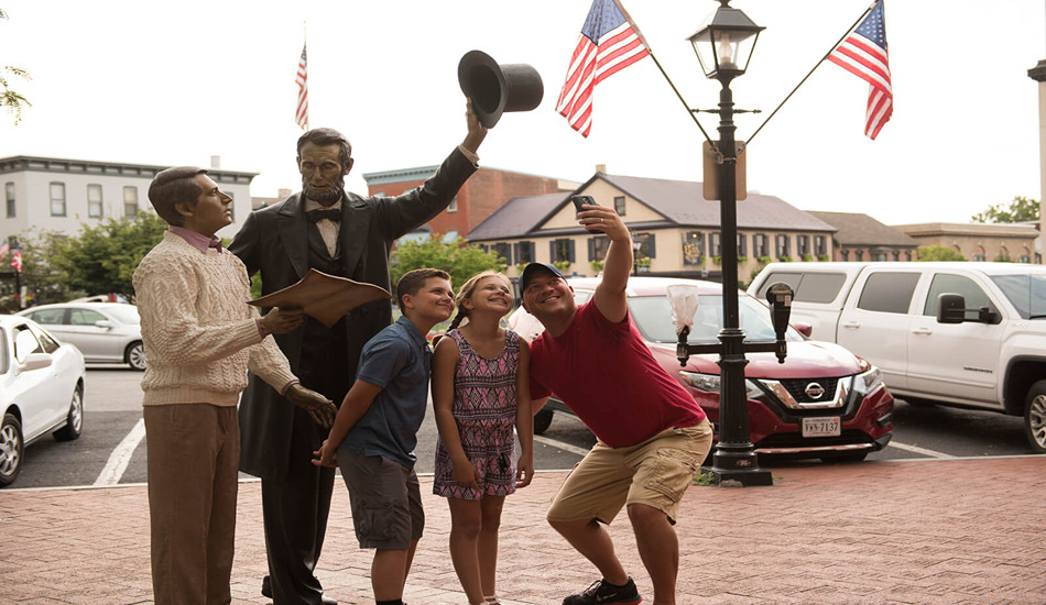 Tourists pose with the statue of Abraham Lincoln in downtown Gettysburg. (Photo credit: Destination Gettysburg)