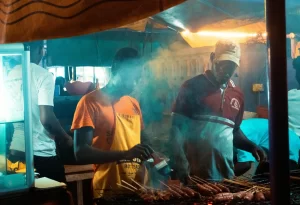 Two Men Cooking Meat on Barbecue Grill