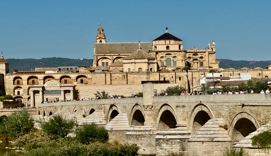 The Roman Bridge, a wide pedestrian walkway, spans the Guadalquivir River.