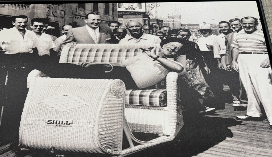 Comedian/actor Jimmy Durante clowning around in a rolling chair on the Atlantic City Boardwalk.